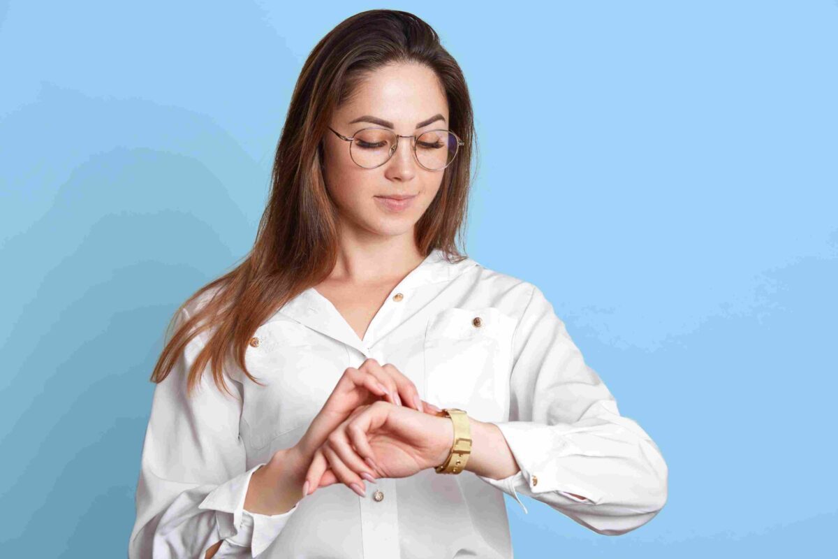 A woman looking carefully at her gold watch